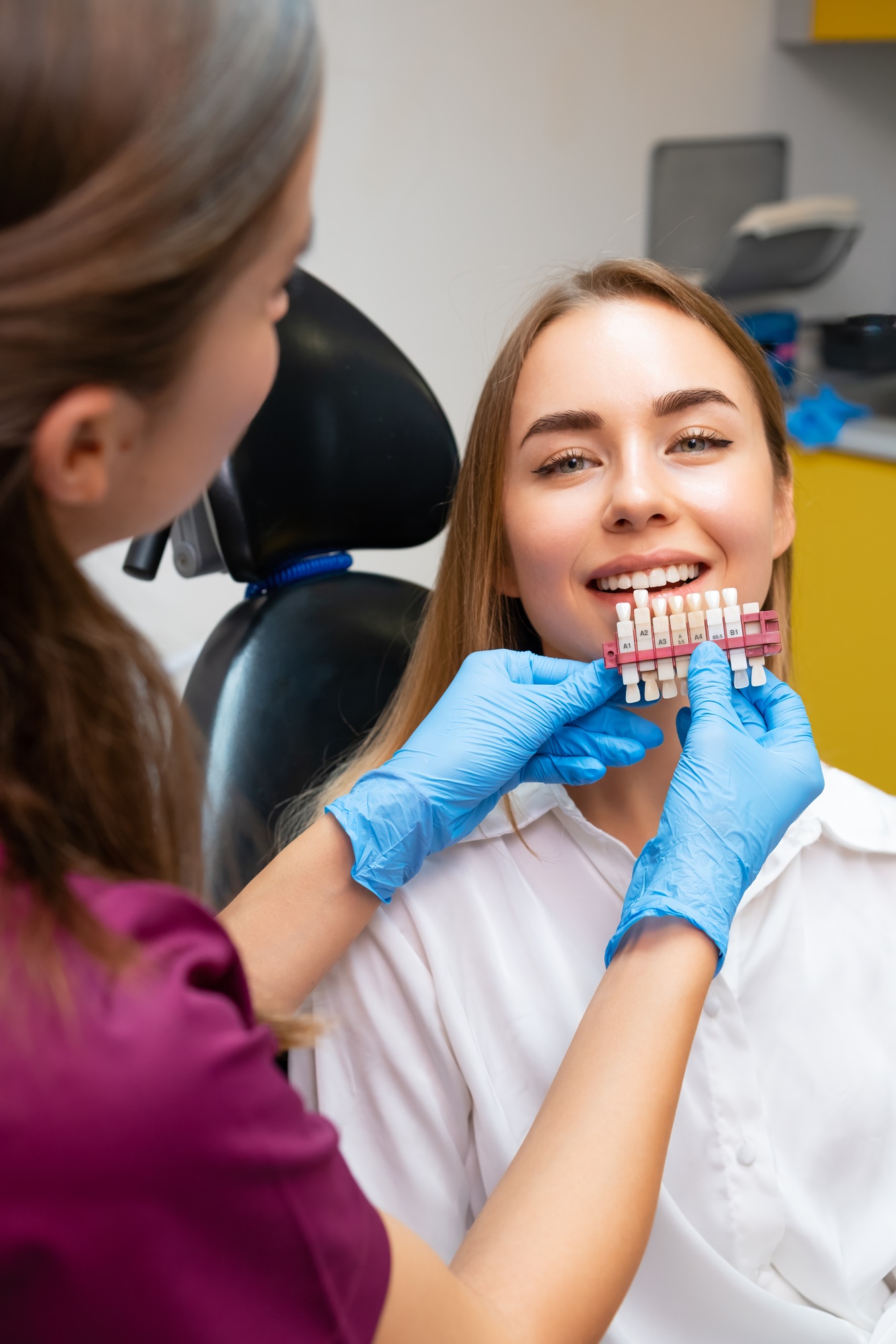 Dentist matching the shades of teeth before whitening procedure for young patient