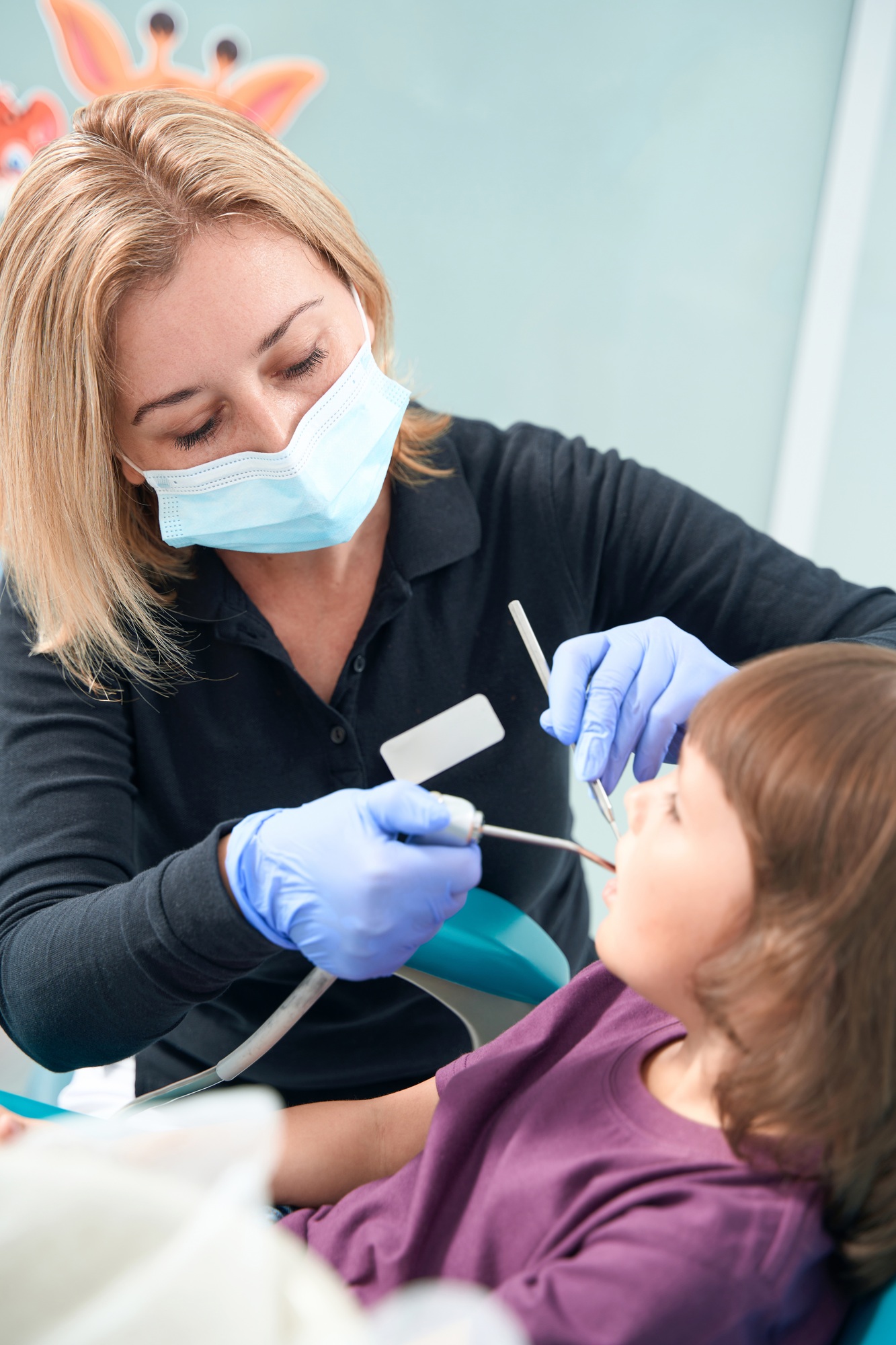 Pediatric dentist examining little girl with dental instruments